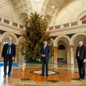 Übergabe der Christbäume an die Staatskanzlei: Der 2. Vorsitzende der Waldbesitzervereinigung Starnberg, Ludwig Groß, Staatsminister Dr. Florian Herrmann, MdL, und der Geschäftsführer der Evangelisch-Lutherischen Pfründestiftung in Bayern, Jörg Heinzler (v.l.n.r.), im Kuppelsaal der Staatskanzlei.